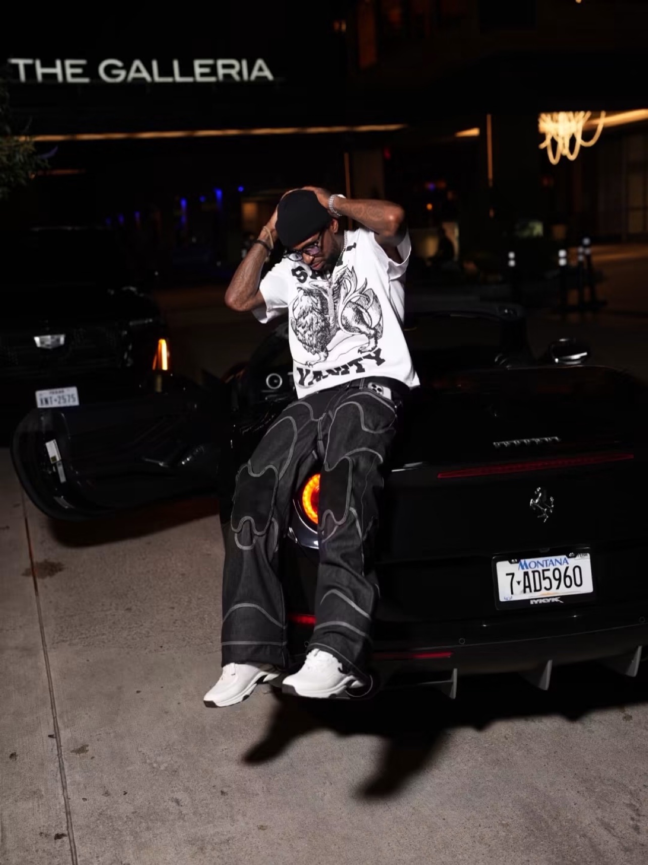Bossman Yayo sitting on the back of a black Ferrari at night outside The Galleria