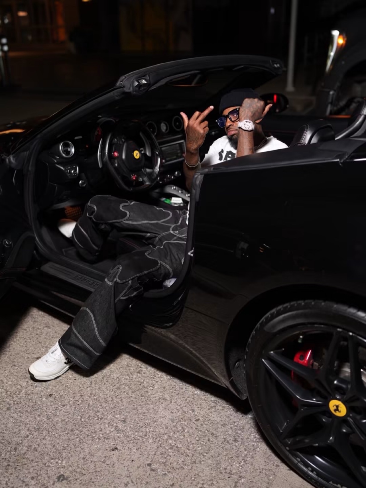 Bossman Yayo in the driver's seat of a black Ferrari convertible